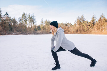 person running in winter. Woman in sportswear, hat and gloves trains outside in winter. Workout in...