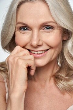 Happy pretty 50s middle aged woman touching healthy soft face skin, smiling, looking at camera. Anti age healthy skincare treatment and cosmetic ads. Face close up view crop detail headshot portrait