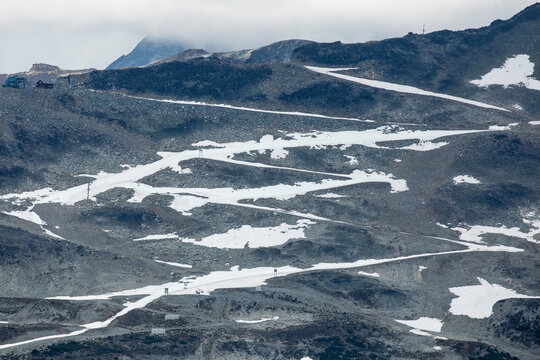 An alpine road covered in snow zig zags up a mountain and leaves a white line, in the Coast Mountains of British Columbia.