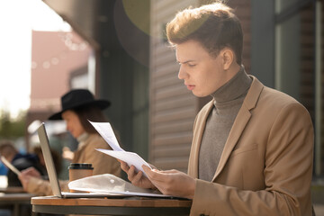 Young confident businessman in smart casualwear looking through business papers