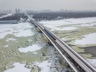 One train on Kiev metro bridge across the frozen Dnieper river. Textured pattern on ice. Aerial...