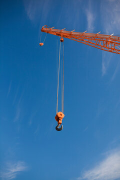 Low angle view of hook hanging on crane against blue sky