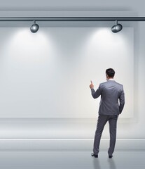 Businessman pressing virtual button on the wall lit with spotlig