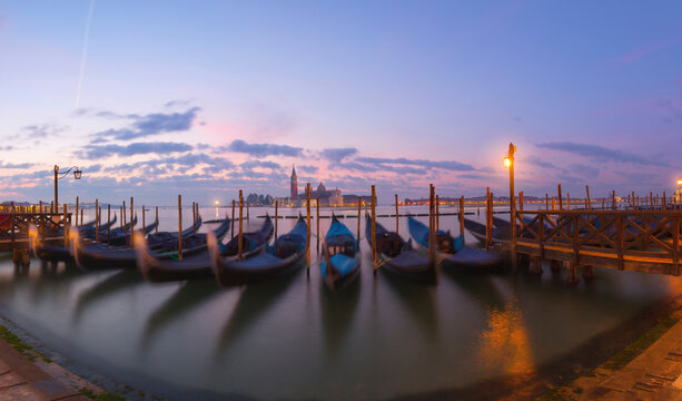 Gondolas moored on Grand Canal against sky during sunrise