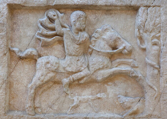 Ancient bas-relief on funerary stele from Kerameikos in Athens, Greece depicting rider in hunting scene. Gravestone of Attica-type