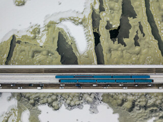 Two metro trains on Kiev bridge across the frozen Dnieper river. Textured pattern on ice. Aerial drone view. Winter frosty morning.