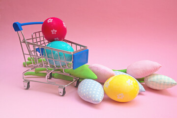 Plakat Painted easter eggs in shopping trolley and spring tulips flowers on pink background with copy space. Easter eco shopping and zero waste.