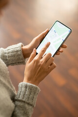 Hands of young female in grey knitted sweater pointing at screen of smartphone