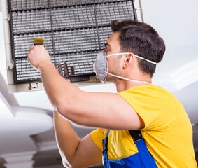 Repairman repairing ceiling air conditioning unit