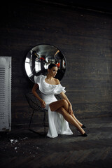 Fototapeta na wymiar Photo portrait of sexy woman wearing white amazing dress stilettos sitting on chair in front wooden wall