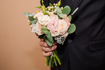 Wedding bouquet with roses in the hands of the groom