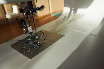 leg and needle with blue thread on a white sewing machine side view