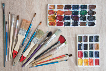 Top view of the artist's workplace. Diverse brush of different lengths and widths. Palettes with...
