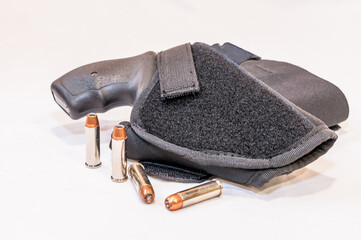 A black snub nose 38 special revolver in a cloth holster with four hollow point bullets next to it...