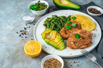 Healthy lunch with juicy chicken breast and avocado with beans on a gray background. The concept of healthy, dietary nutrition.