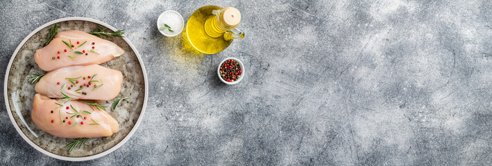 Chicken fillet with herbs and spices on gray table flat lay. Chicken meat with ingredients for cooking. Copy space.
