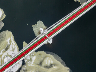 Red-green pedestrian bridge over the Dnieper river in Kiev. Snow patterns on the river. Aerial...