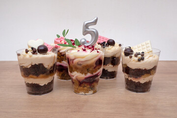 Birthday trifle cake with candle labeled number 5. five portioned mini cakes.
