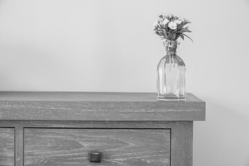 Interior decoration: bouquet of yellow wildflowers in a glass vase on gray wooden background