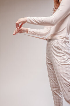 Beautiful sexy woman wearing a beige pajama. Fashion model on a beige background.