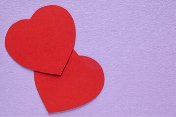 Red cardboard hearts from on a gentle lilac background card