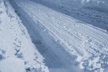 Fototapeta na wymiar The road is completely covered with snow. A rut formed. A lot of snow, it glistens with frost.