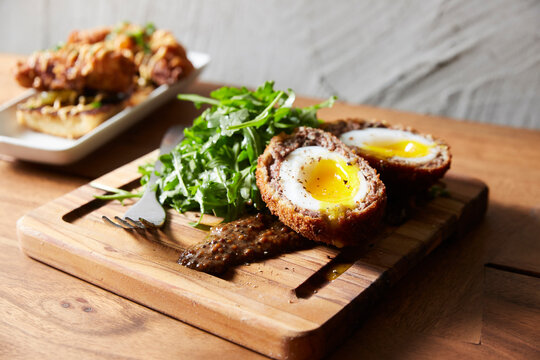 High angle view of scotch eggs with arugula served on serving board