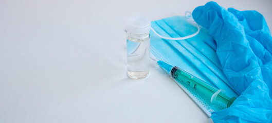 A syringe, gloves, mask, and a bottle of vaccine stand on a blue background. For the prevention, immunization and treatment of coronavirus infection. The concept of medicine and health care