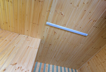 View of a ceiling made of wood clapboard with fixed length LED daylight lamp