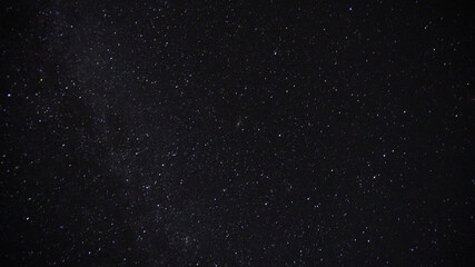 The bright starlight of the night sky. The milky way, meteorites and nebula are visible. The stars illuminate the ground, the grass and the post. Night landscape of the starry sky.