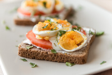 Sliced pumpernickel bread with eggs, tomatoes and sour cream.