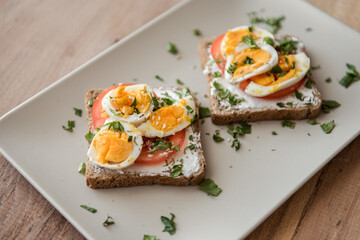 sliced bread with eggs, tomatoes and sour cream. Diet sandwich on plate.