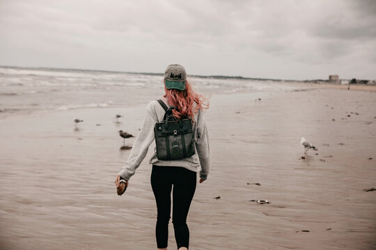 Young girl wearing backpack carries a shell down the beach