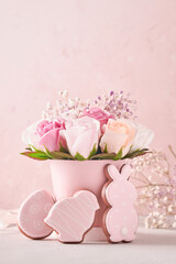 Easter background decoration with beautiful bouquet pink roses flowers in vase, Easter eggs, bunny and chick on pink background table. Easter concept with copy space.