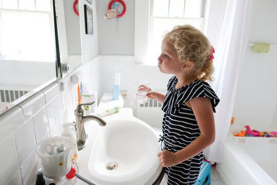 Side view of girl washing mouth while looking into mirror in bathroom