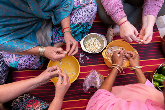 A detail shot of diverse women's hands preparing garlic..