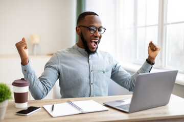 Fototapeta na wymiar African Businessman At Laptop Shaking Fists Shouting In Joy Indoor
