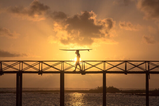 man carrying surfboard on bridge of cloud 9 siargao Philippines