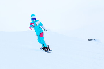 woman snowboarder is snowboarding from the mountain 