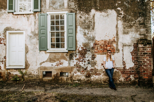 A woman leans against a brick wall in Charleston, South Carolina