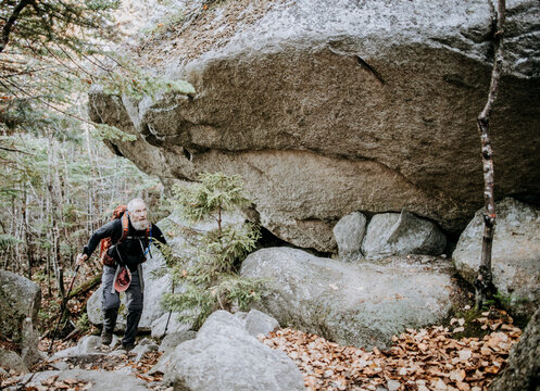 A retirement age male hikes beneath a boulder on the Appalachian Trail