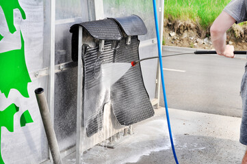 Washing car mats with high pressure water in car wash