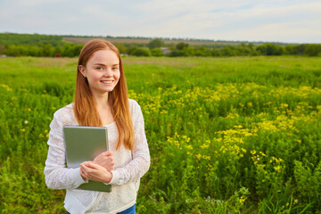 girl working in nature with a laptop lying on the green grass. The girl works as a freelance traveler.