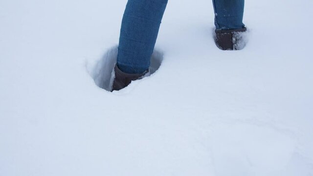 Legs walking on snow with footprints. rear view. camera follows the legs.