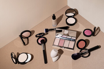 decorative cosmetics for makeup, brushes and sponges for the face on a beige geometric background.