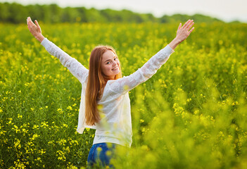 Naklejka na ściany i meble woman with open arms in the green rapeseed field.