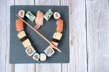 Heart-shaped sushi set on a slate plate and wooden tabletop