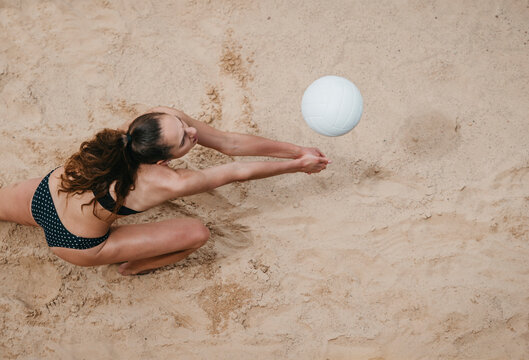 Professional player with white ball playing beach volleyball on sand. Summer vacation and sport concept
