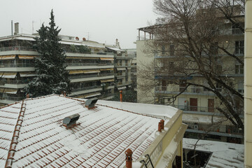 Medea front hits with heavy snowfall the city center in Thessaloniki, Greece. Snow falling on residential area with blocks of flats surrounded be trees.