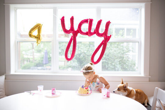 Cute girl and corgi dog at table with cake birthday party